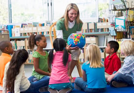 Elementary school teacher using a globe to teach her class about geography.