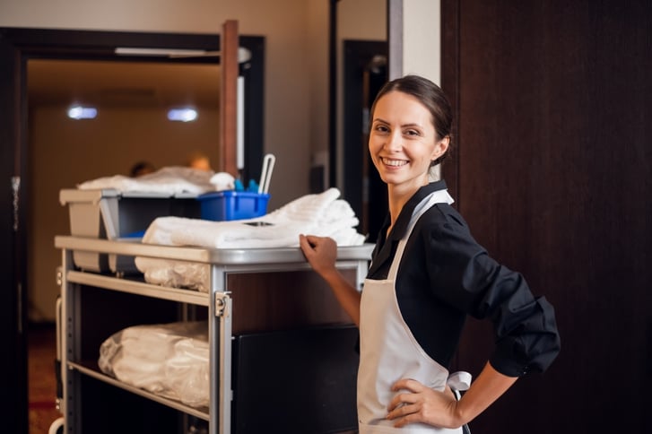 housekeeper with cart in hotel hallway